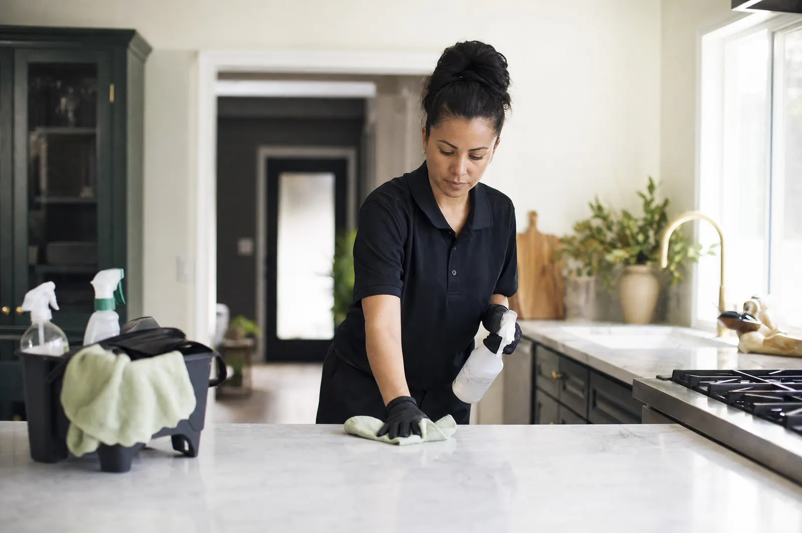 A house cleaner wipes down a kitchen counter